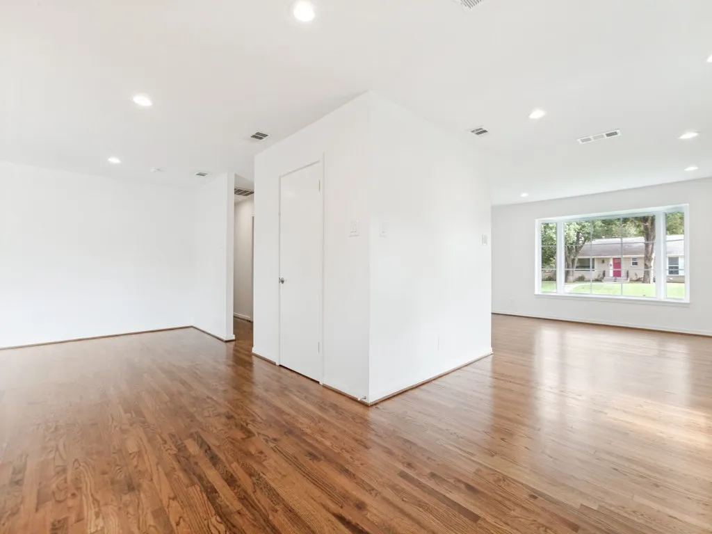 Spacious open-concept room featuring wood-finish flooring, recessed lighting, white walls, and a large multi-pane window