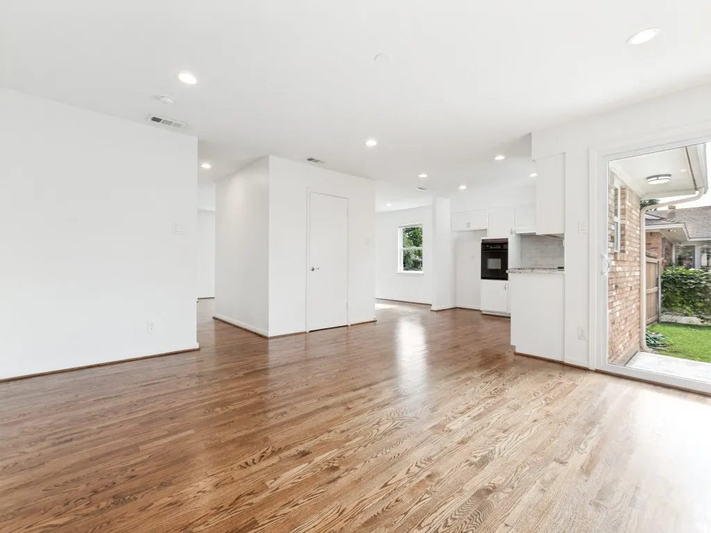Expansive interior featuring rich wood-finish flooring, recessed lighting, and crisp white walls