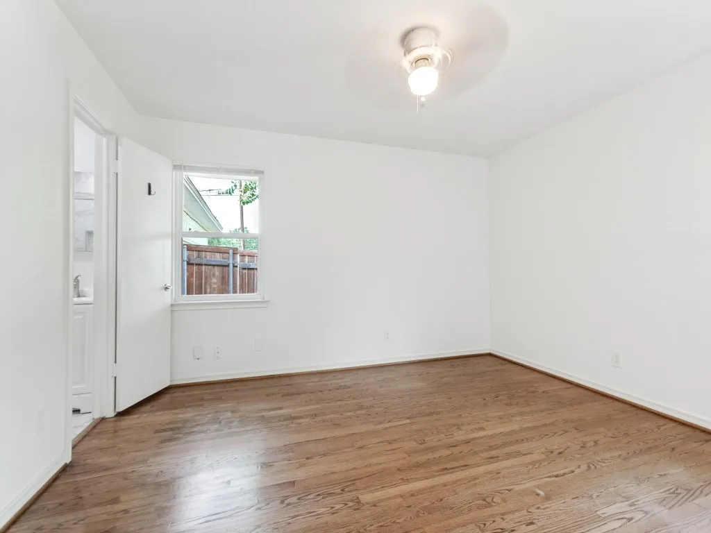 Bright interior space featuring wood-finish flooring, a ceiling-mounted light fixture, and a window providing exterior light