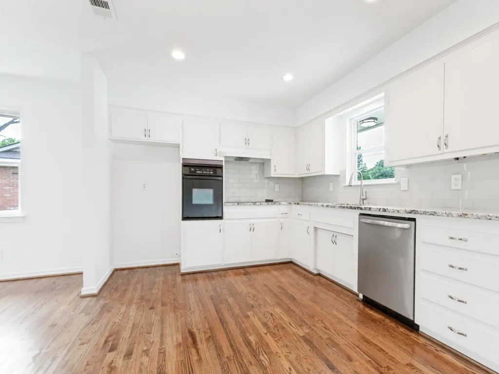 Kitchen featuring white cabinetry, granite-patterned countertops, a tile backsplash, wood-finish flooring, and recessed lighting