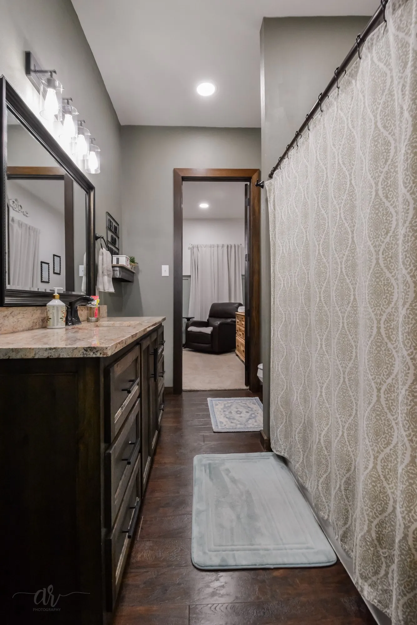 Bathroom featuring a dark wood-finish vanity with a light-colored countertop, an overhead vanity light fixture, and wood-finish flooring