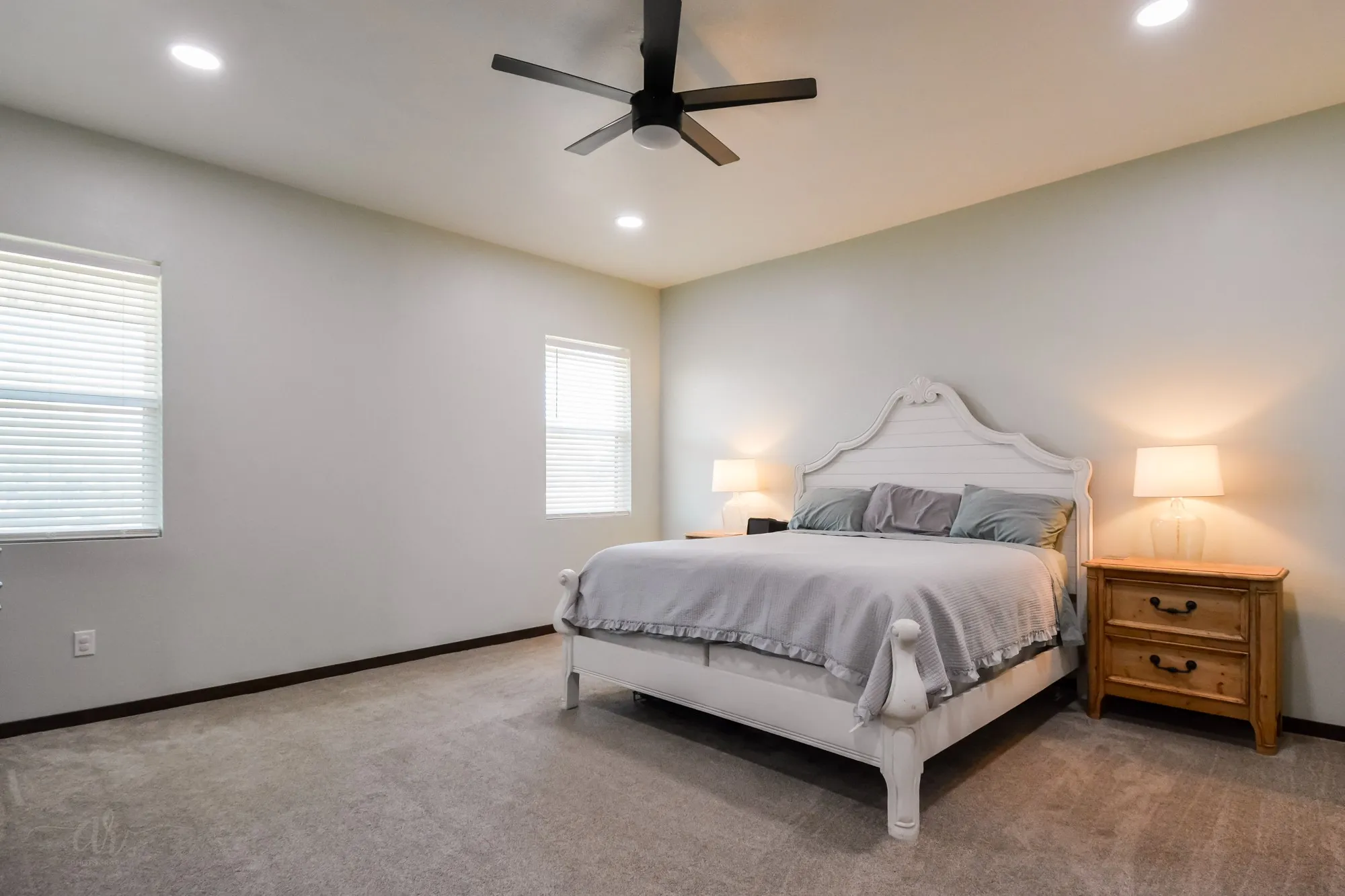 Spacious room featuring neutral carpeting, a ceiling fan with integrated lighting, recessed ceiling lights, and multiple windows with blinds