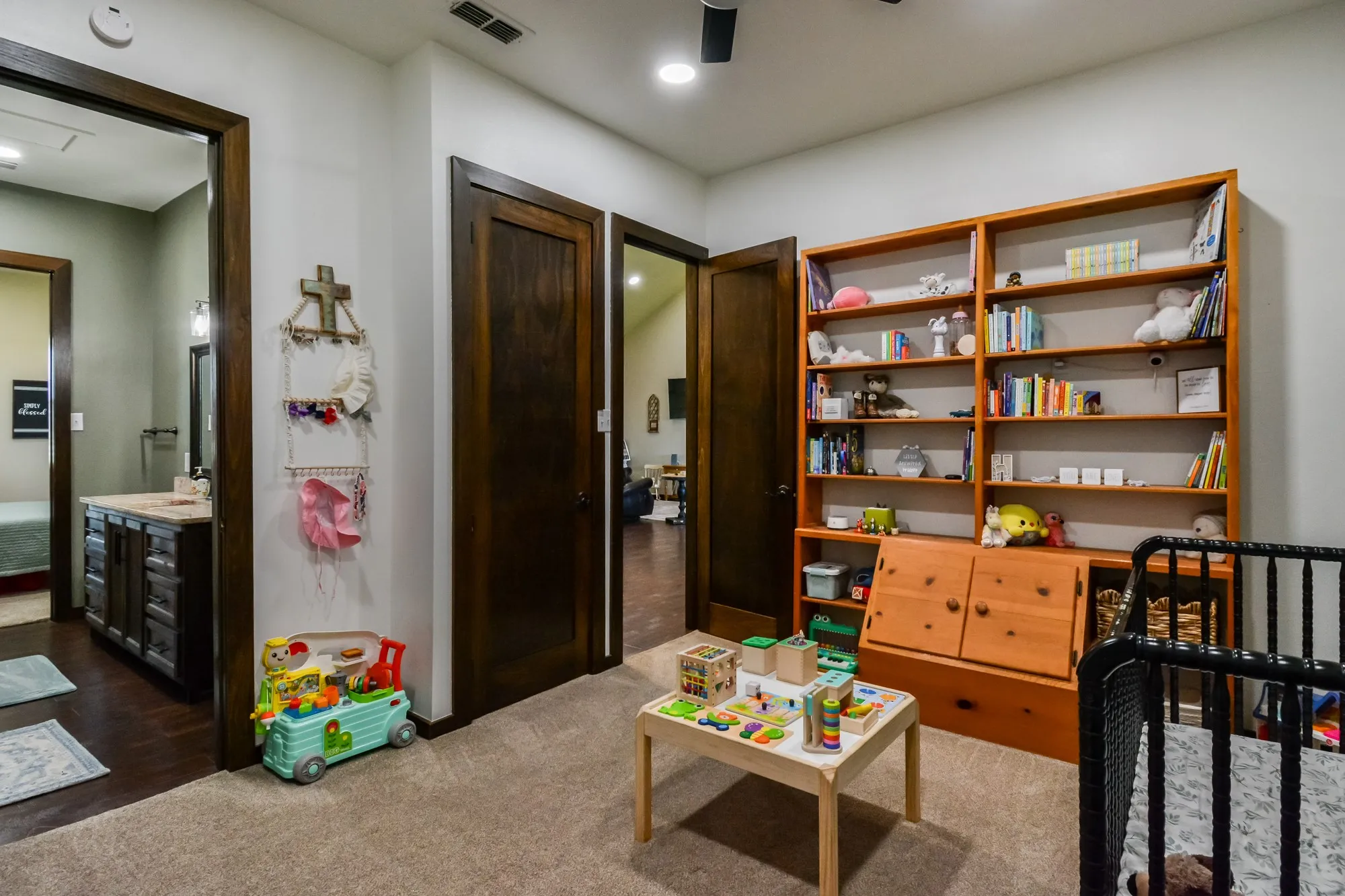 Carpeted room featuring a built-in wooden bookcase, dark wood-finish doors, and recessed lighting