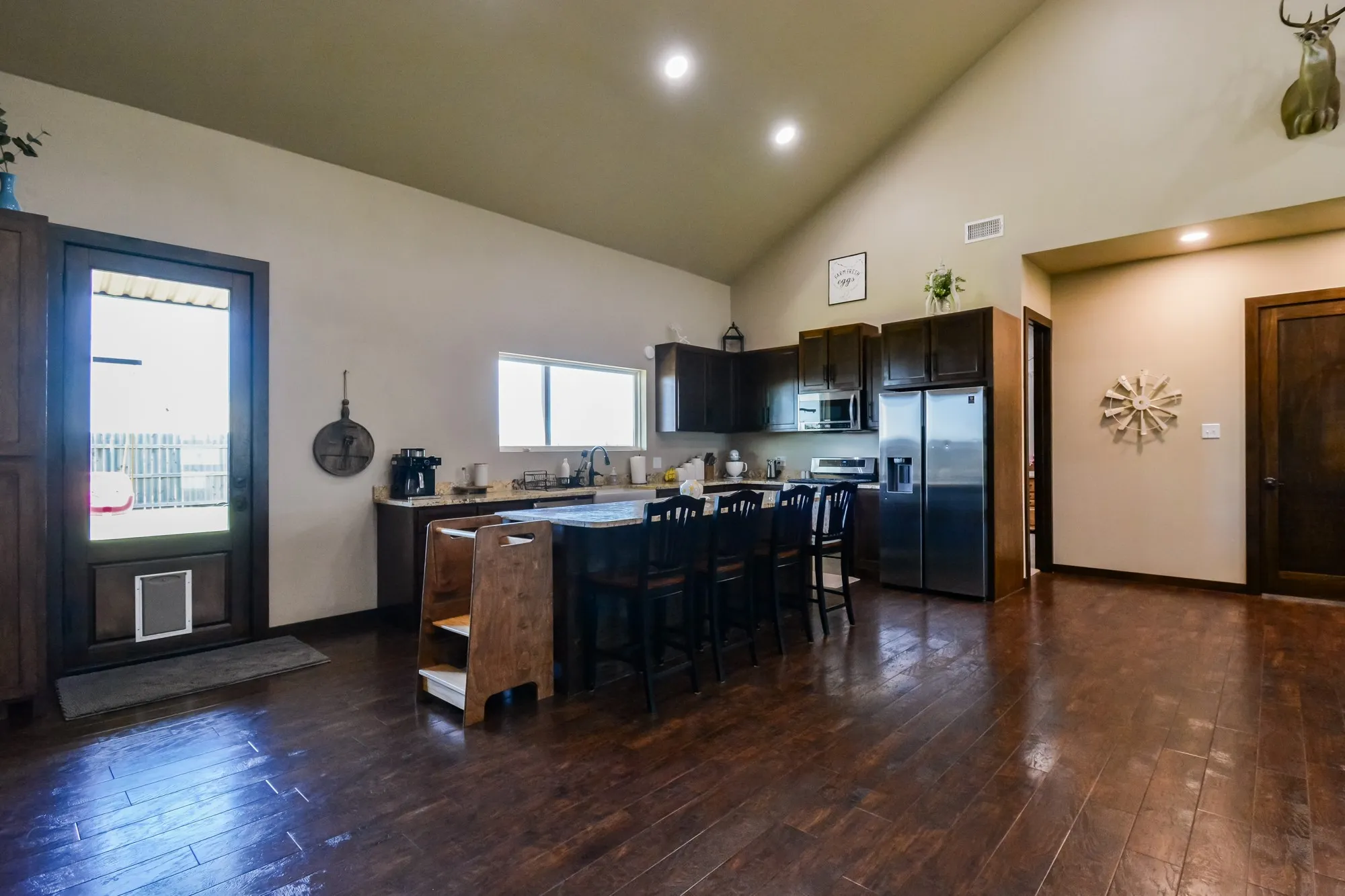 Kitchen featuring wood-finish flooring, dark wood cabinetry, a central island with seating, stainless steel appliances, and vaulted ceilings