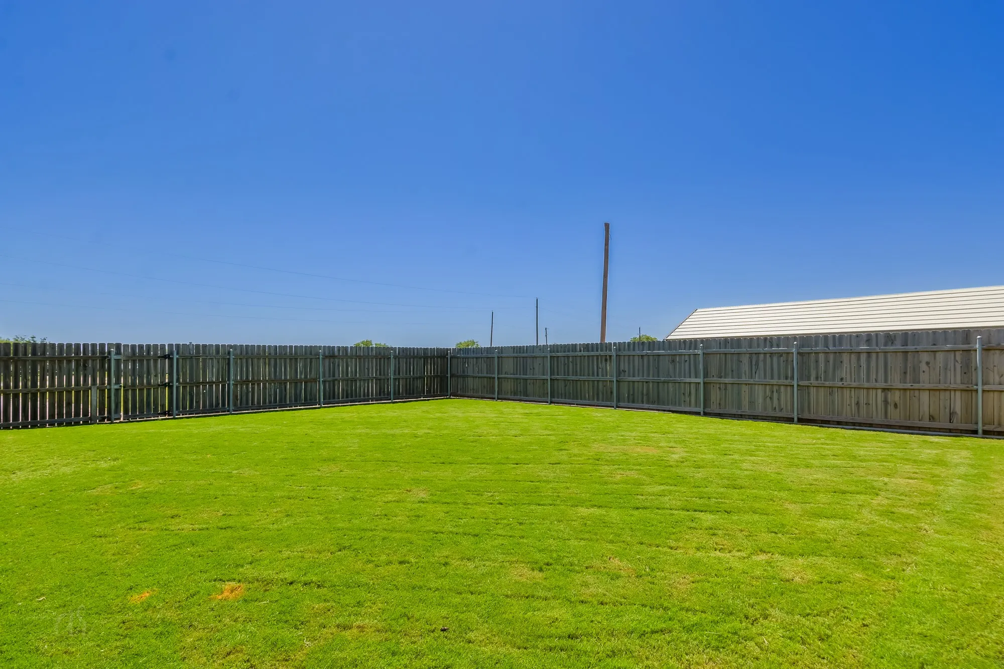 Expansive backyard featuring a lush lawn, privacy fencing, and ample open space