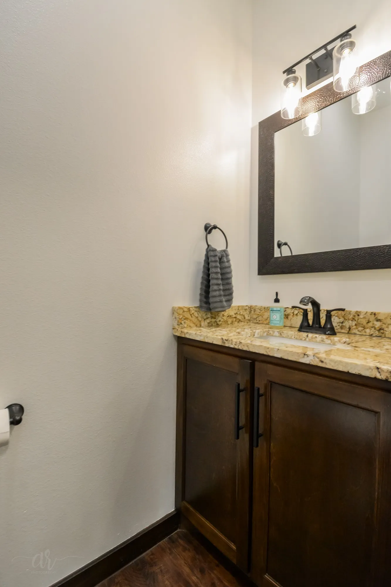 Vanity featuring a granite countertop, undermount sink, and dark wood cabinetry with matte black hardware