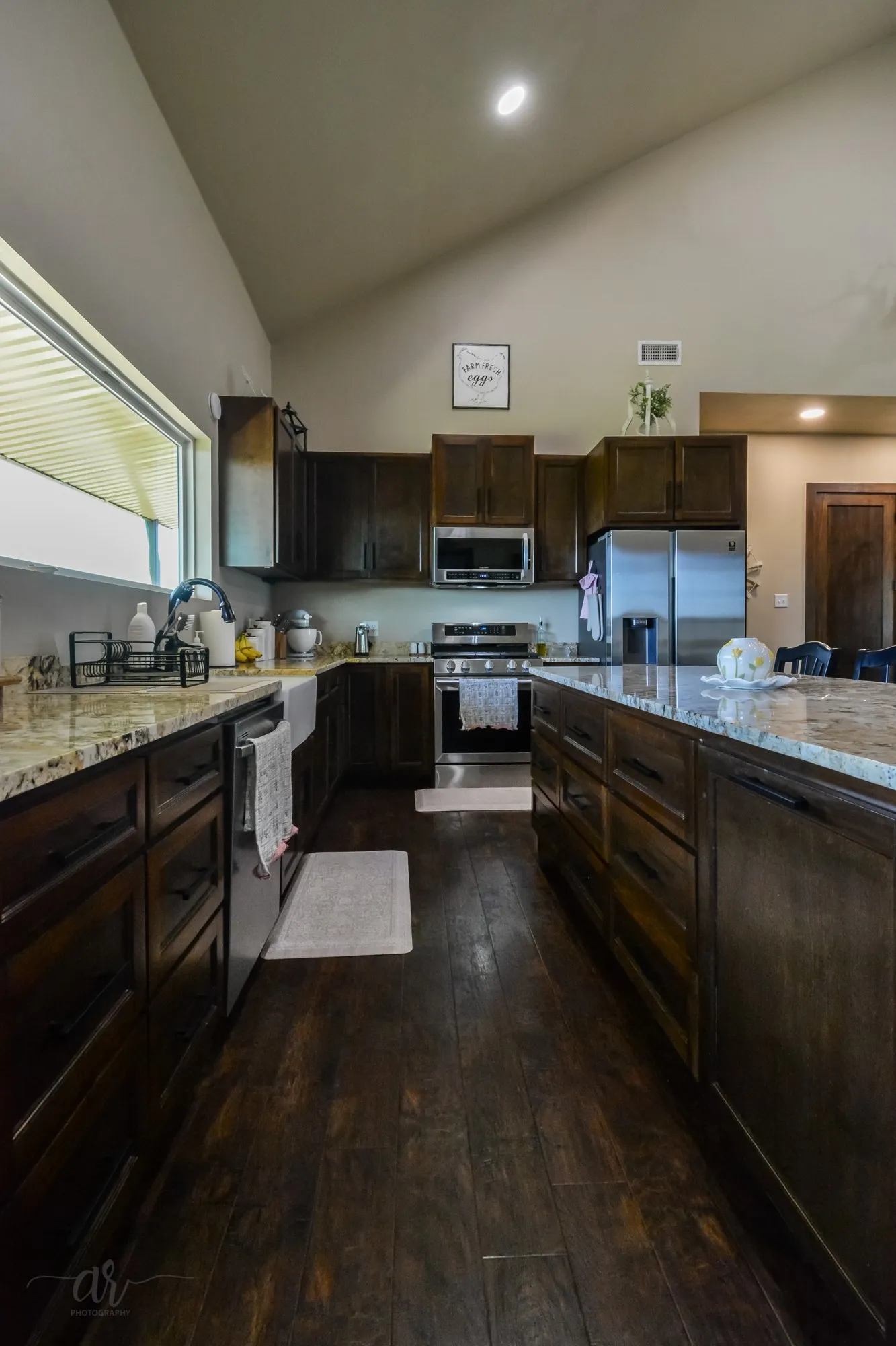 Kitchen featuring dark wood cabinetry, light-toned granite countertops, and stainless steel appliances