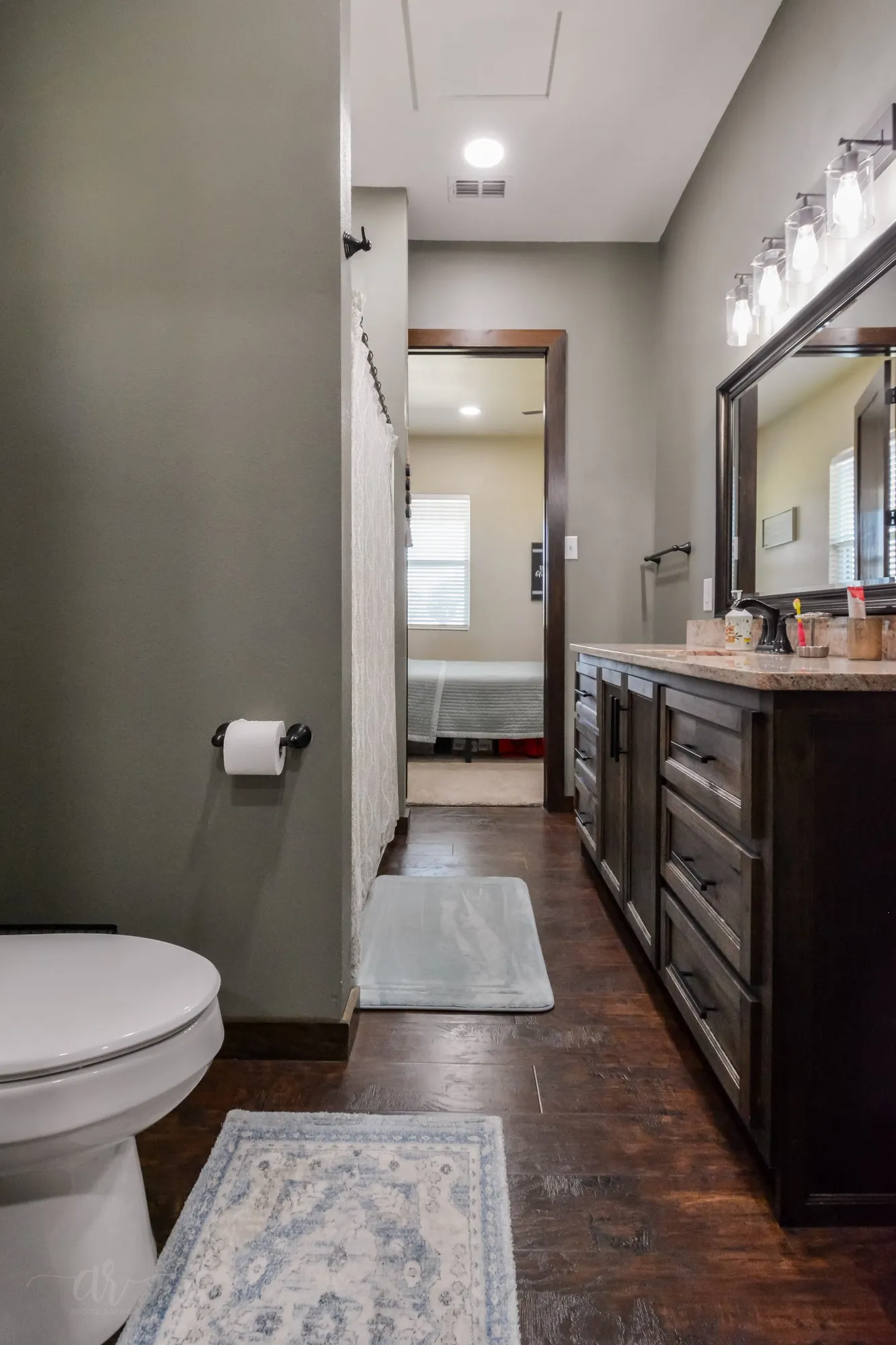 Bathroom vanity with dark wood cabinetry, a light-colored countertop, and a large framed mirror