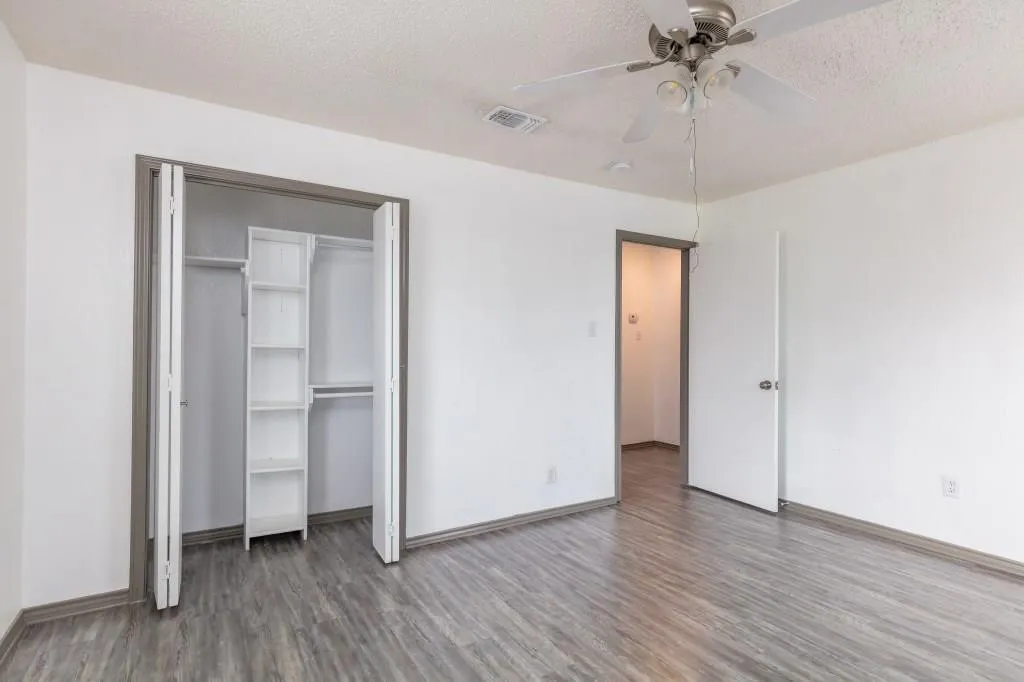 Bedroom featuring wood-finish flooring, white walls, and a ceiling fan with integrated lighting