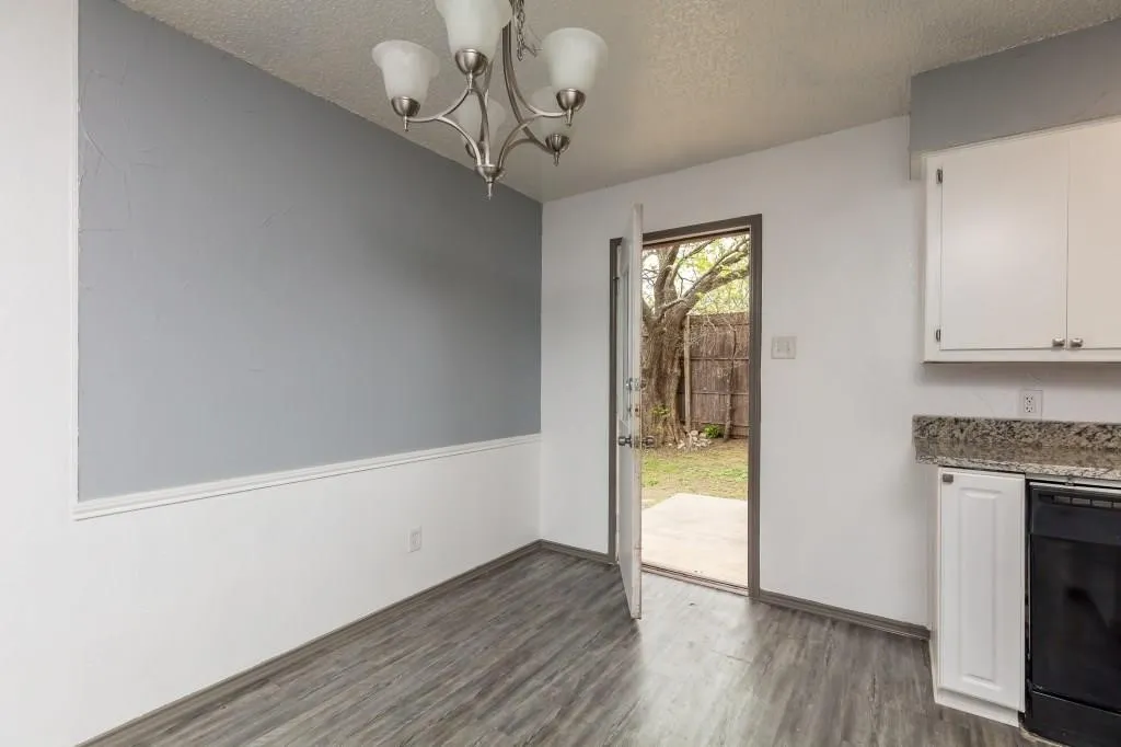 Grey wood-finish flooring with a modern chandelier and direct outdoor access