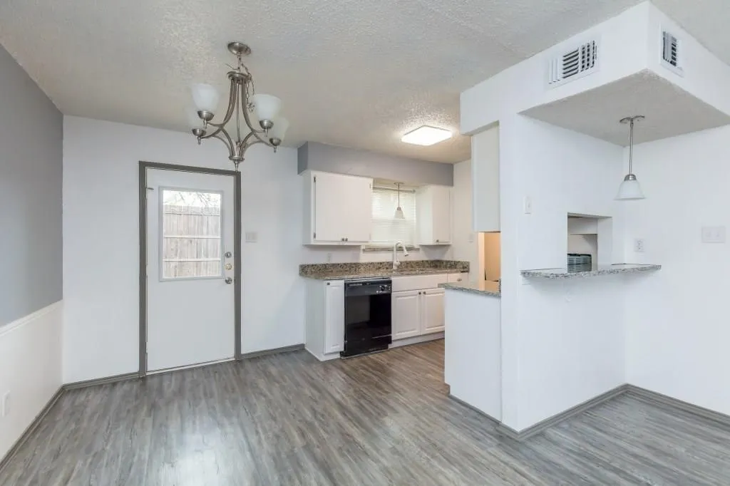 Kitchen and dining area featuring wood-finish flooring, white cabinetry, granite countertops, and a breakfast bar