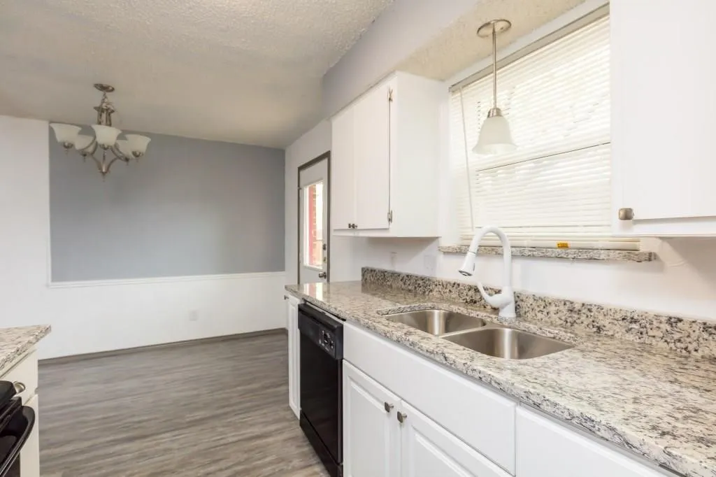 Kitchen featuring white cabinetry, granite-style countertops, and a dual basin stainless steel sink with a gooseneck faucet