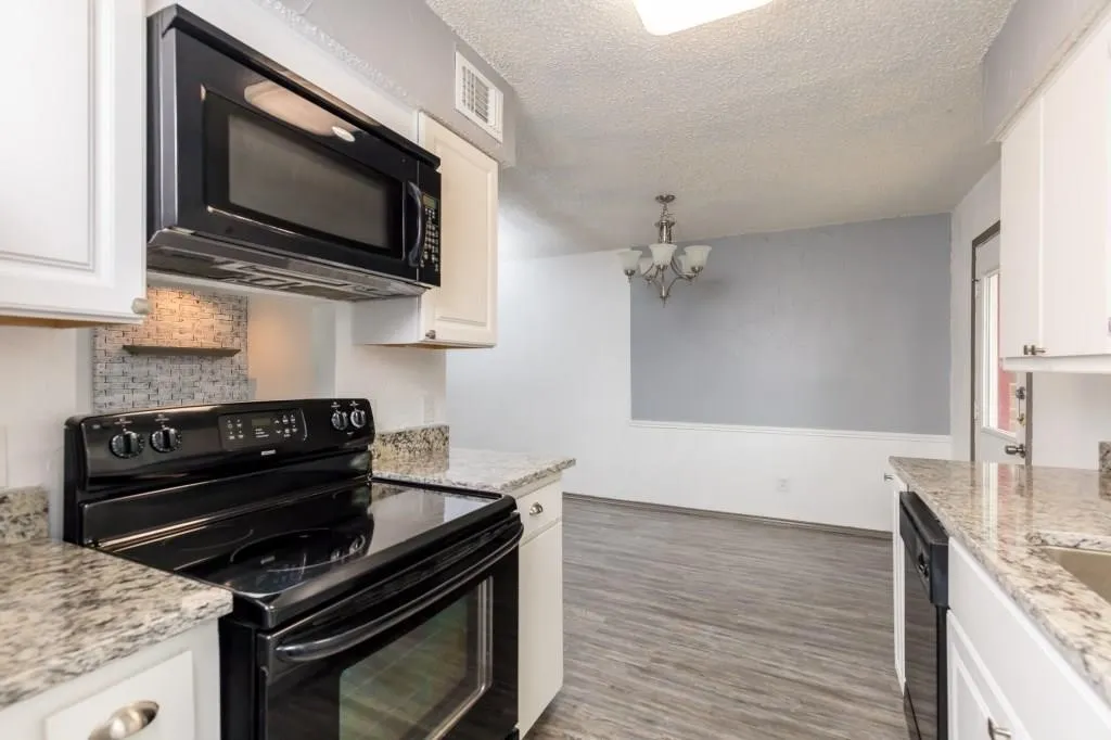 Kitchen featuring granite countertops, white cabinetry, a built-in microwave, an electric range, and a tile backsplash