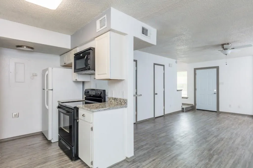 Kitchen area featuring white cabinetry, a black appliance package, and stone-finish countertops