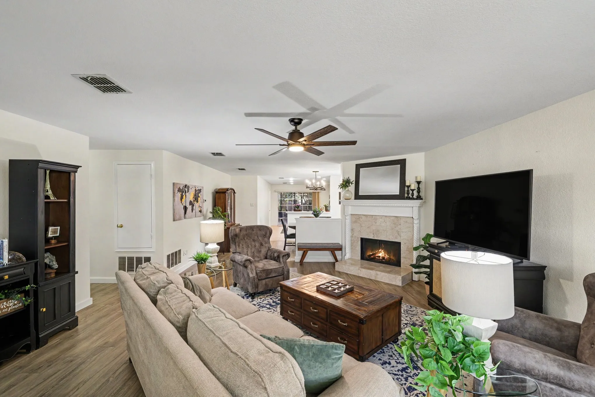 Spacious living room with wood burning fireplace, looks into dining room and kitchen