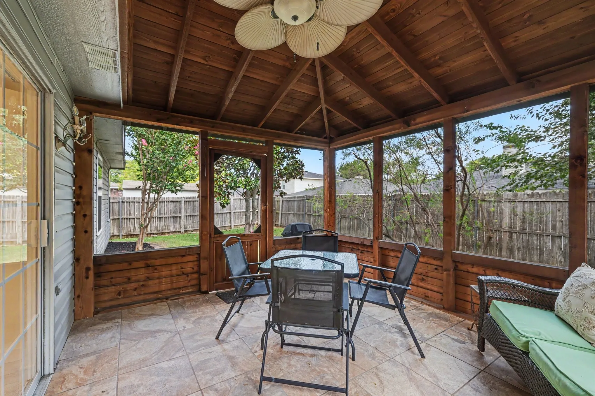 Screened in sunroom with tile flooring and ceiling fan