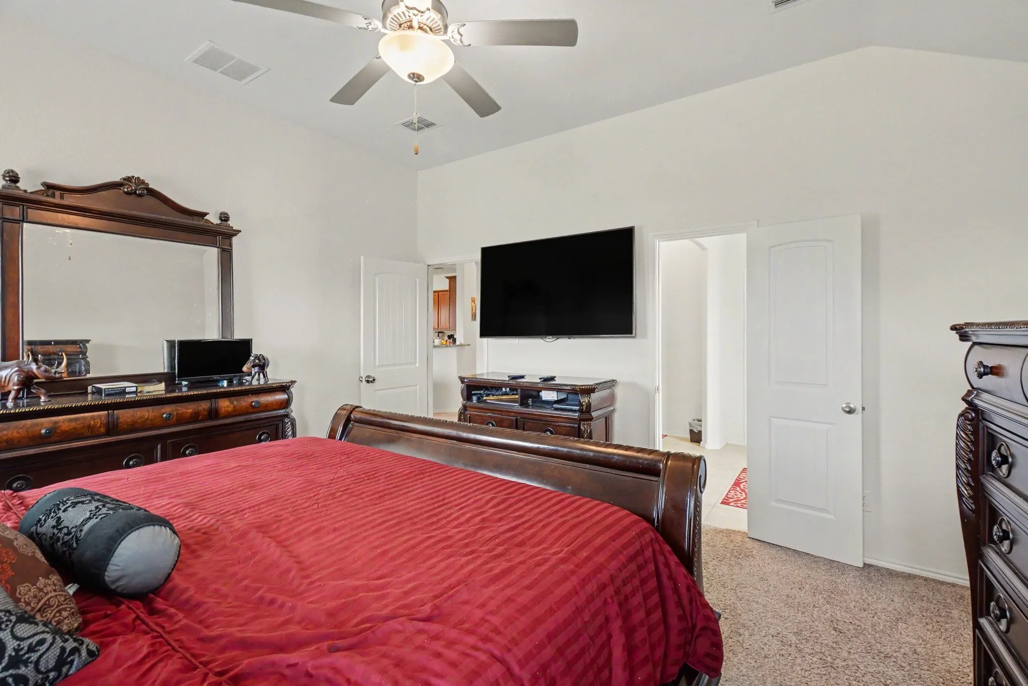 Carpeted room featuring a ceiling fan with integrated lighting, vaulted ceilings, and white paneled doors