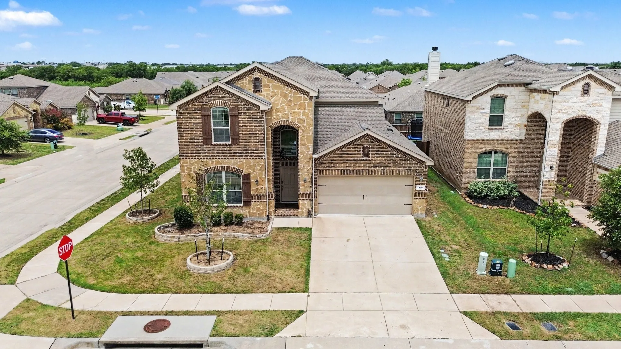Two-story residence featuring a brick and stone facade, arched entryway, and an attached two-car garage
