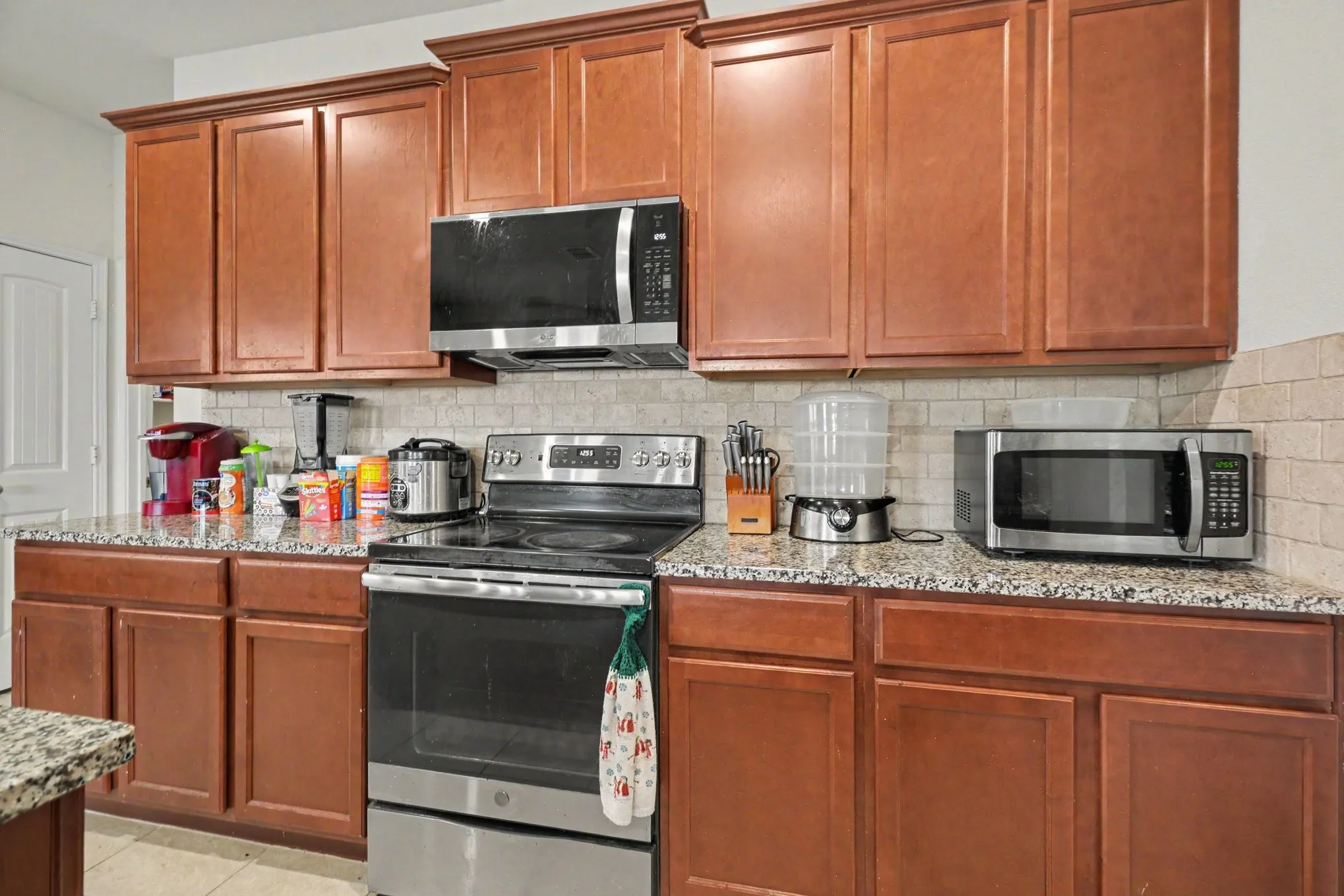 Kitchen featuring wood-finish cabinetry, granite-style countertops, and a subway tile backsplash