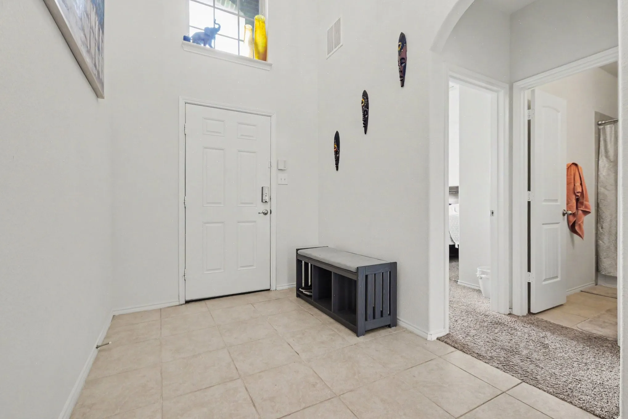 Foyer entrance featuring a white panel door, high ceilings, and an upper transom window