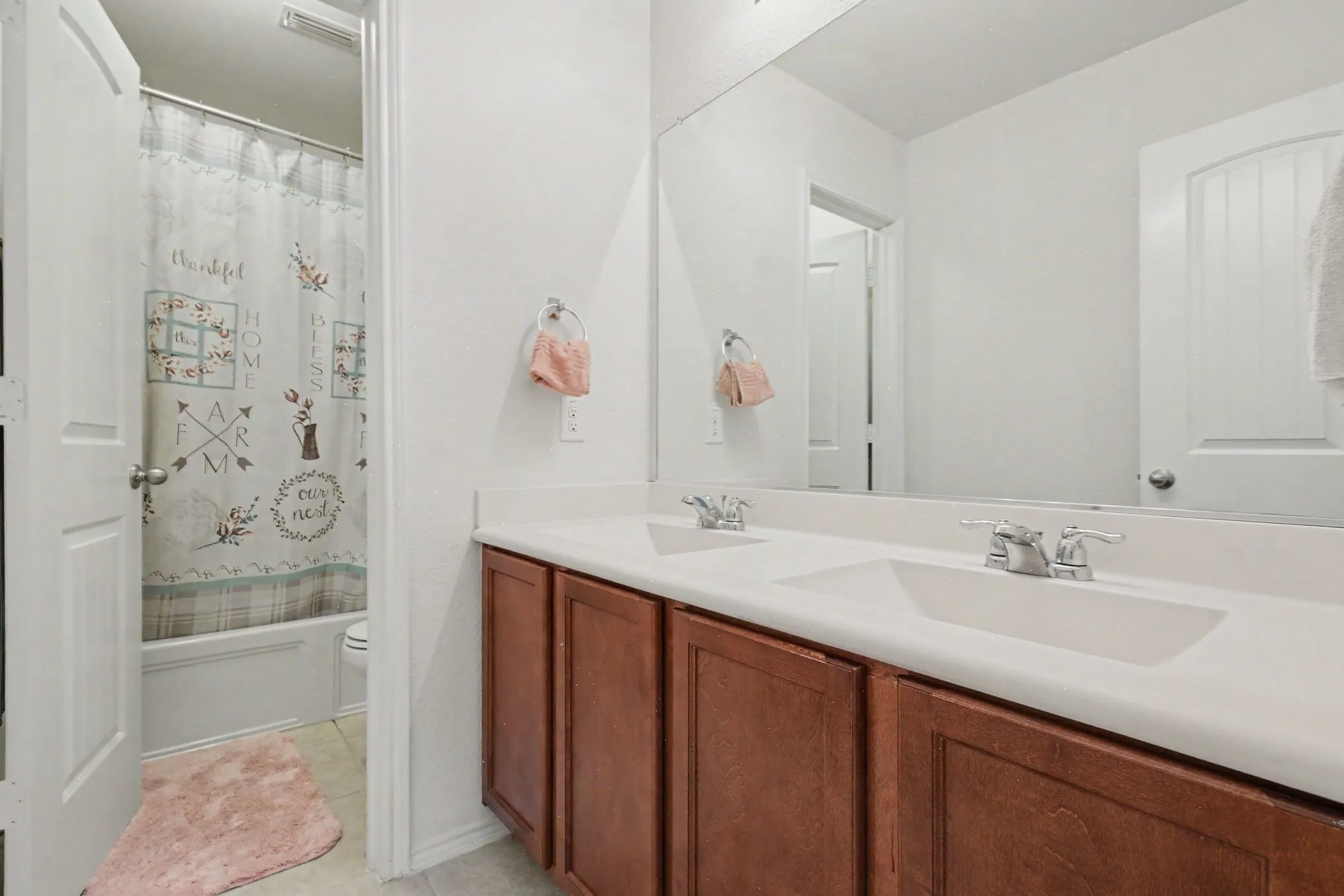 Double vanity featuring integrated sinks, chrome faucets, and wood-finish cabinetry