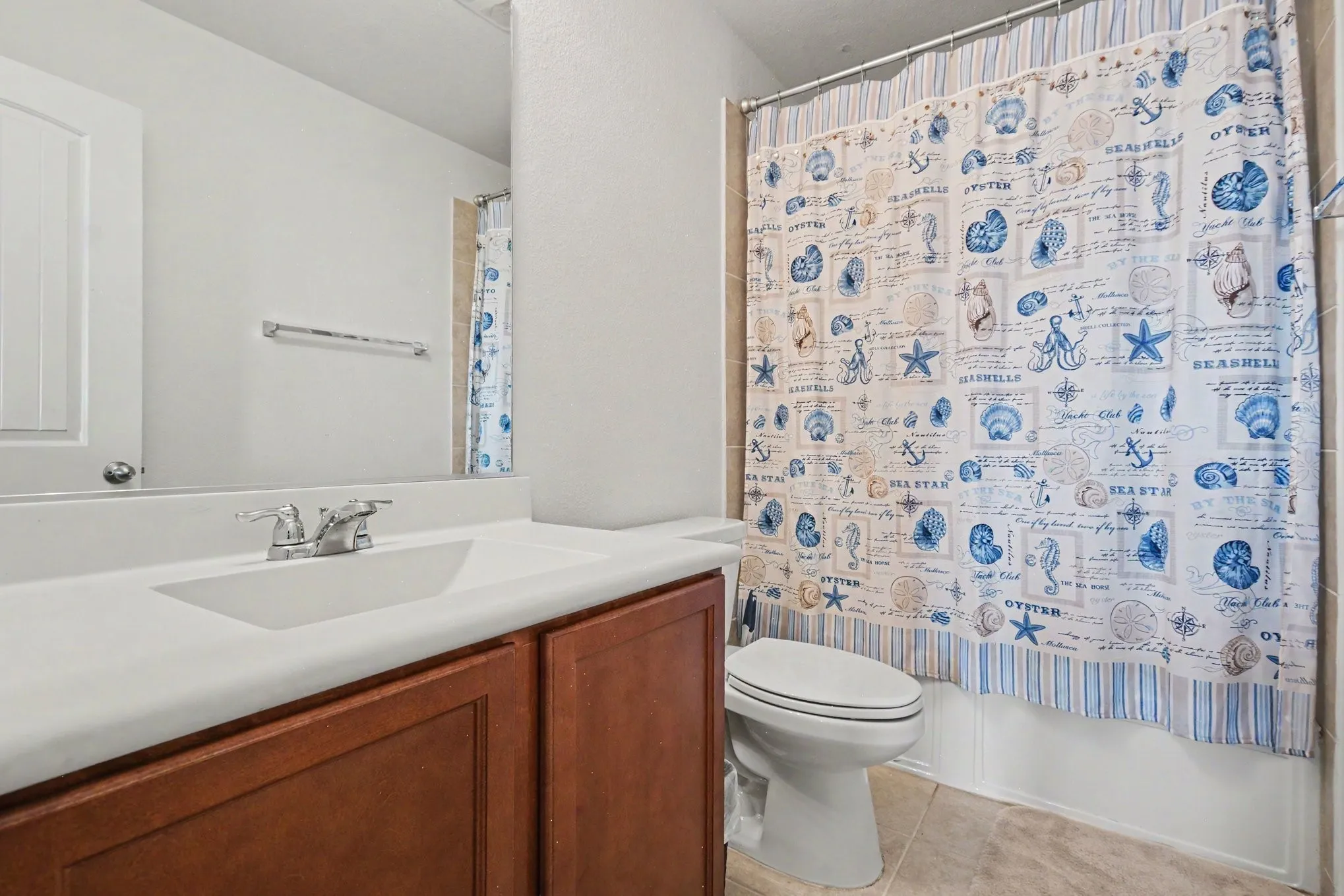 Full bathroom featuring a single vanity with a white countertop and wood-finish cabinetry, a mirror, and a bathtub with a shower