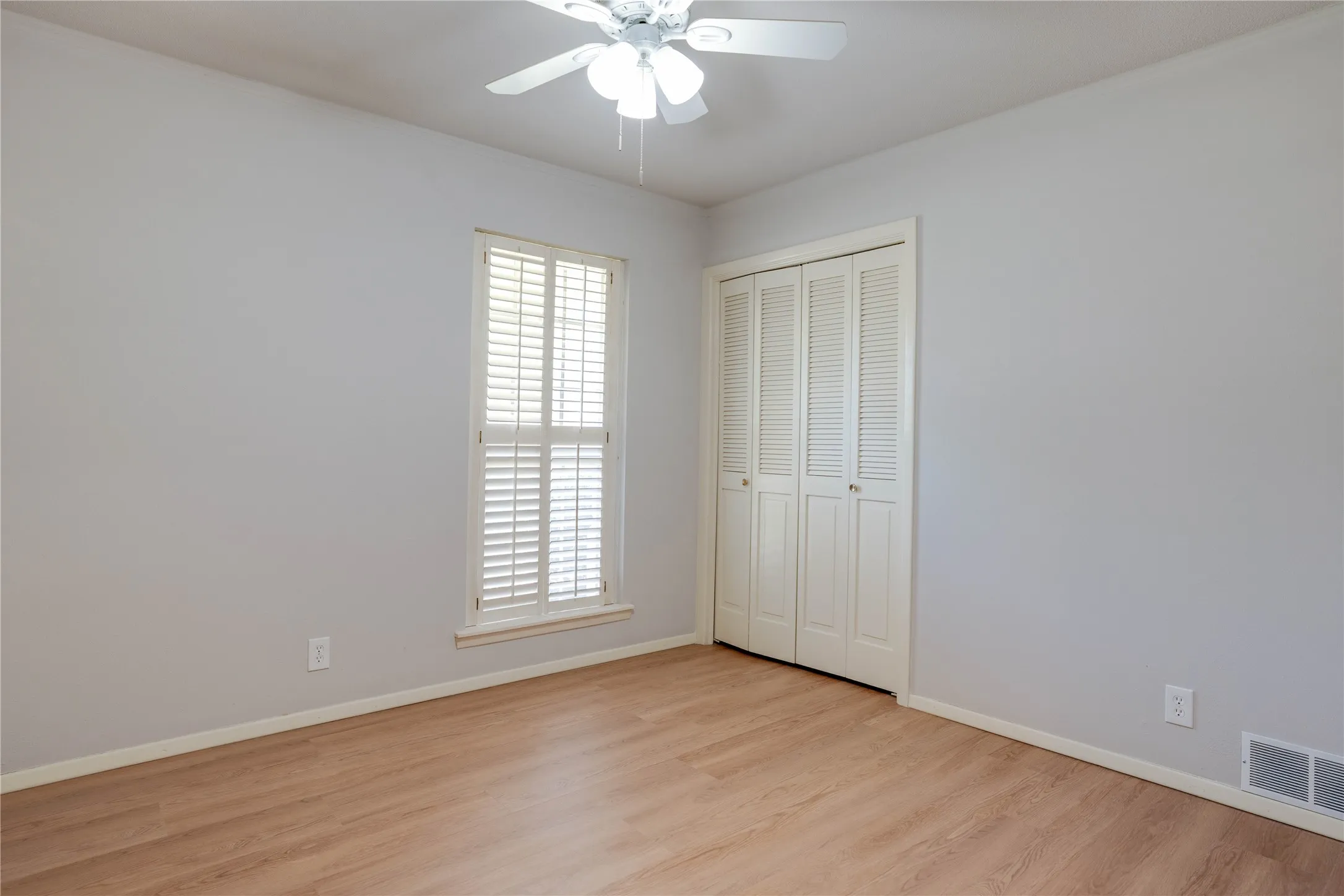 Bright room featuring light wood-finish flooring and a white ceiling fan