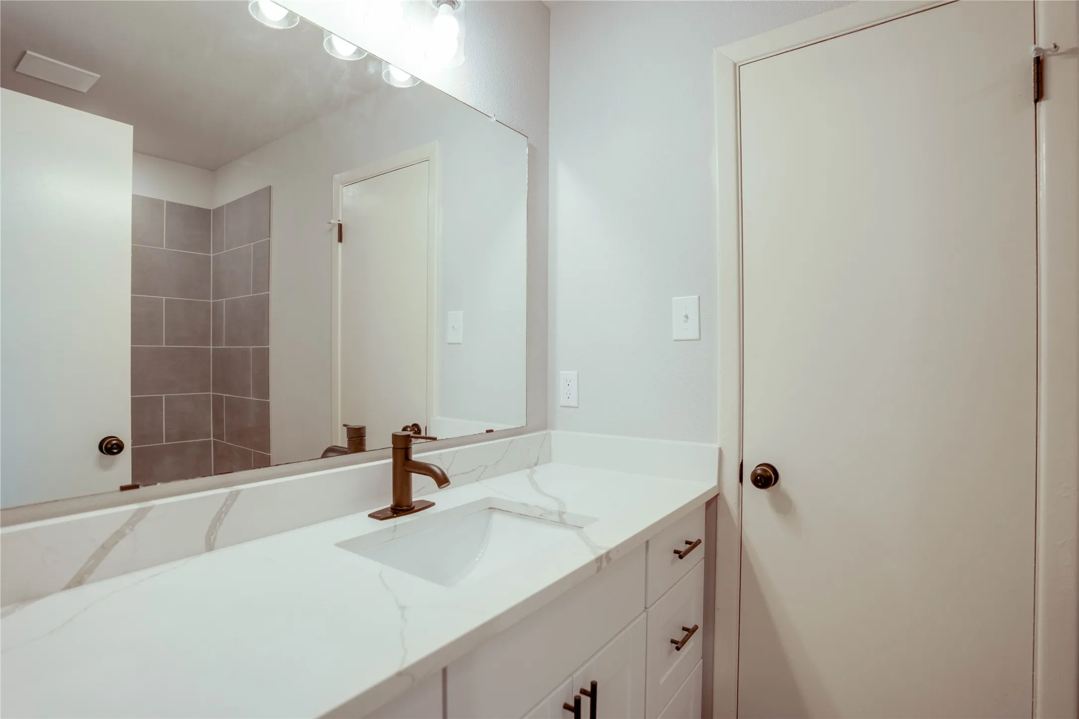 Bathroom vanity featuring a quartz-finish countertop with an integrated rectangular sink