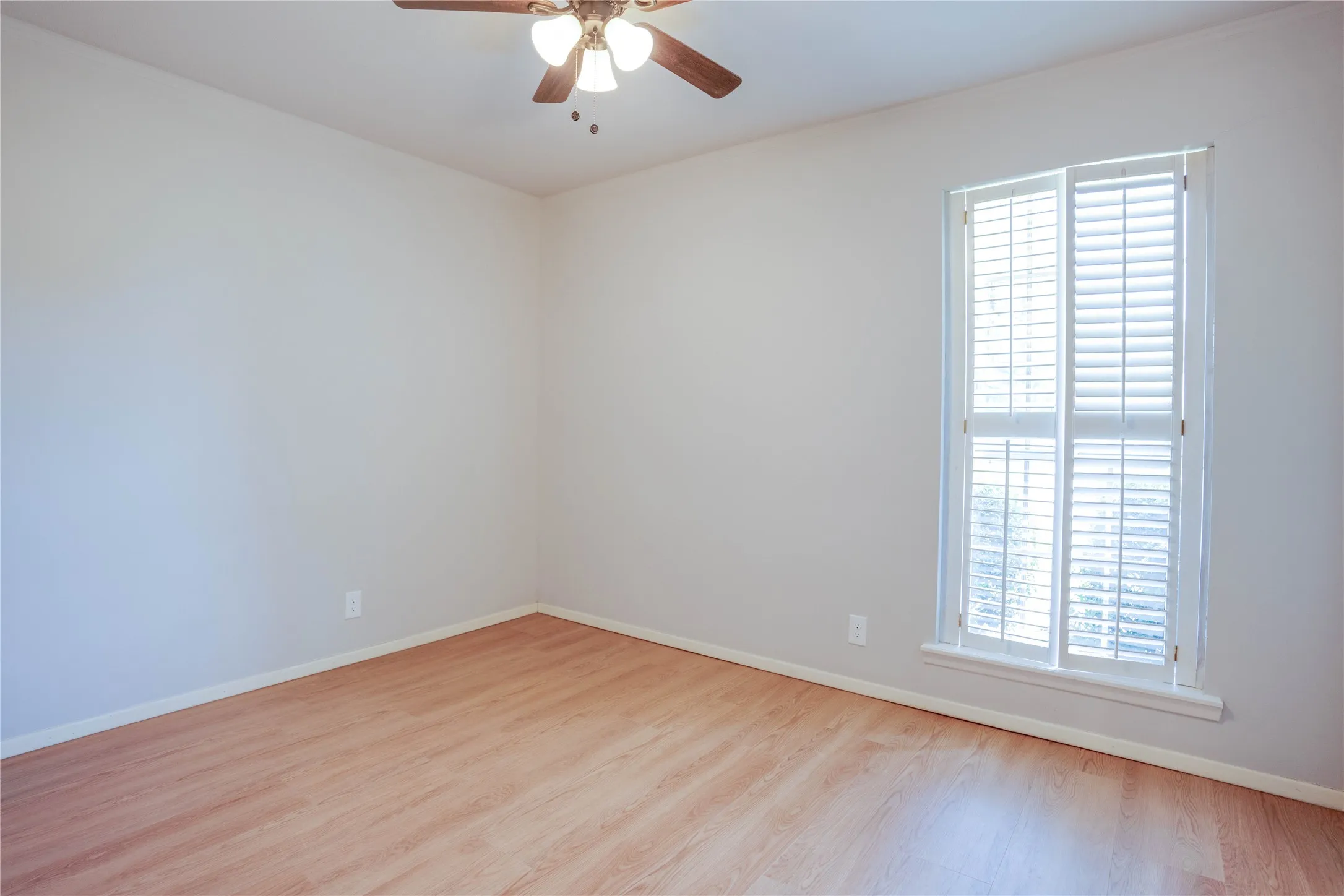 Room featuring wood-finish flooring, white baseboards, and neutral wall tones