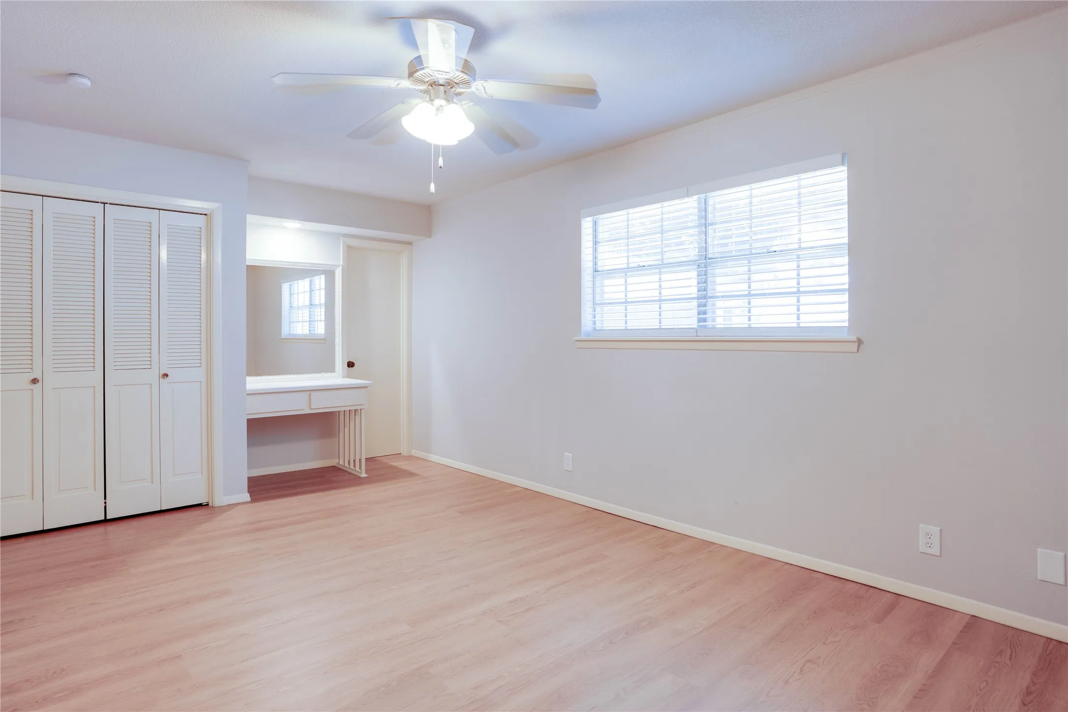 Spacious room featuring wood-finish flooring and a ceiling fan
