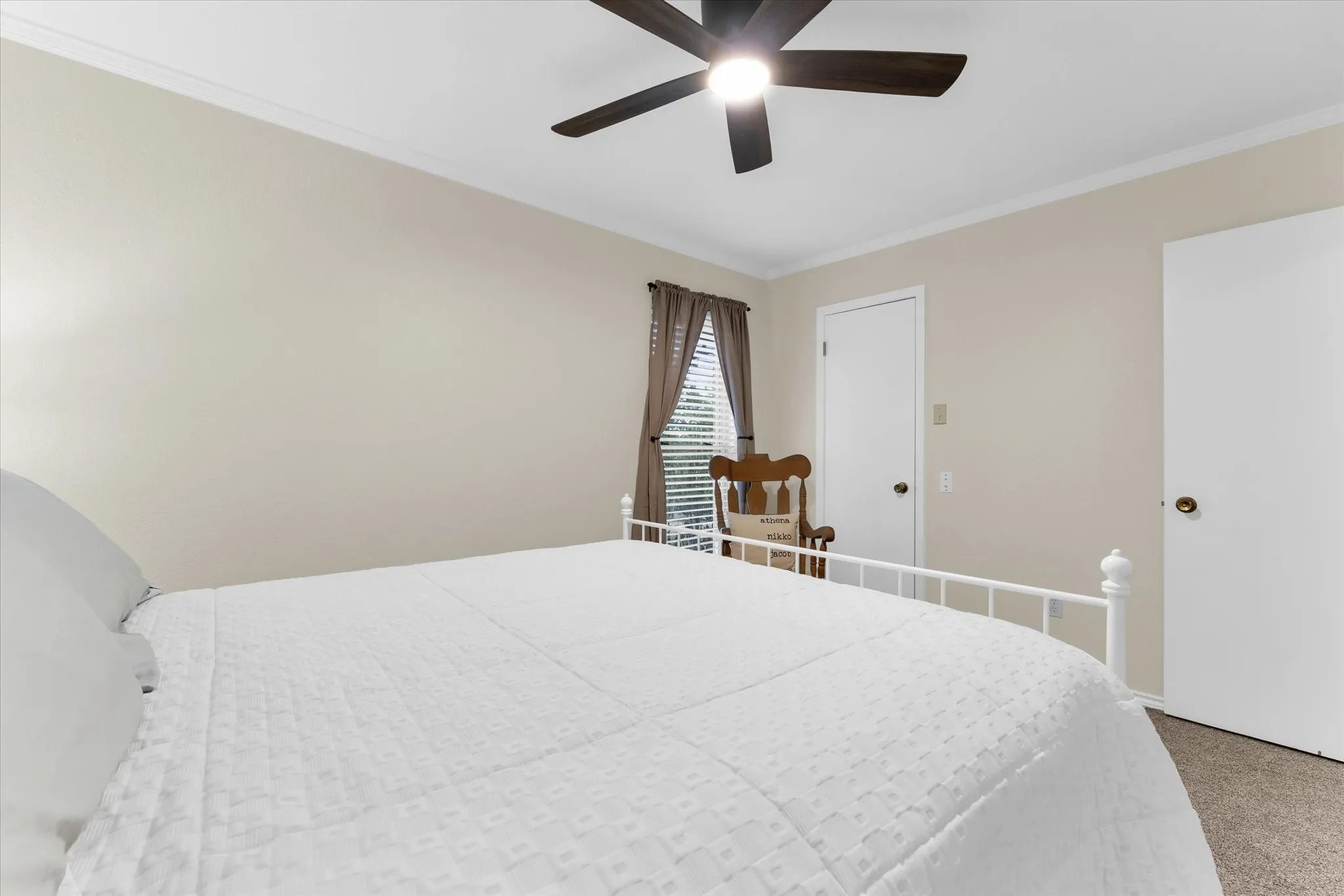 Neutral-toned interior featuring a ceiling fan with integrated lighting, crown molding, white trim, and carpet flooring