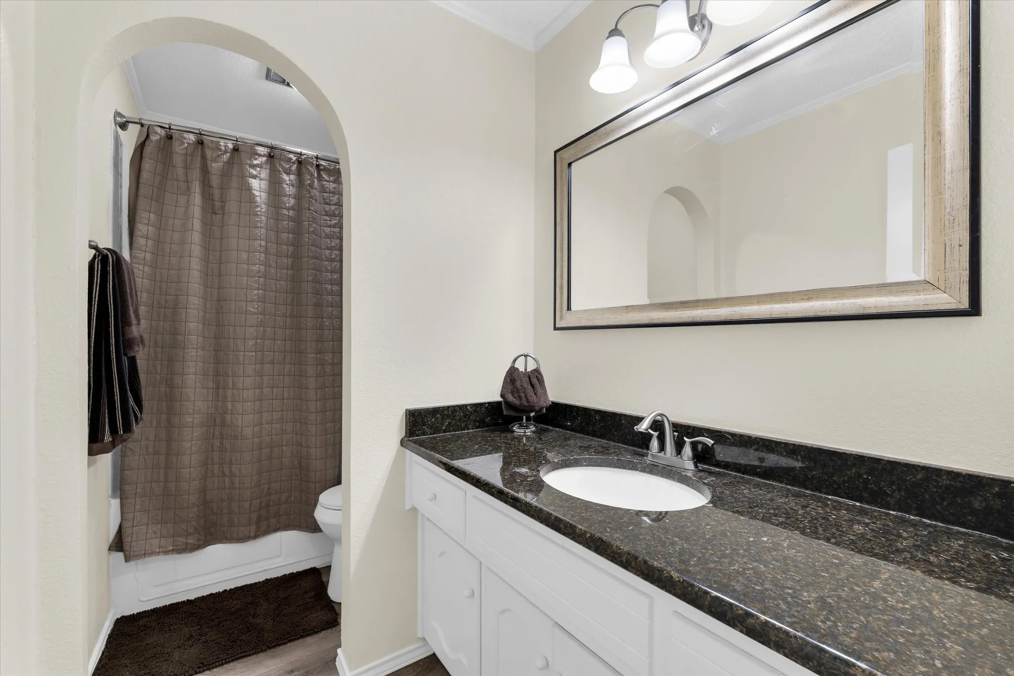 Bathroom vanity featuring a dark speckled countertop, undermount sink, and chrome faucet