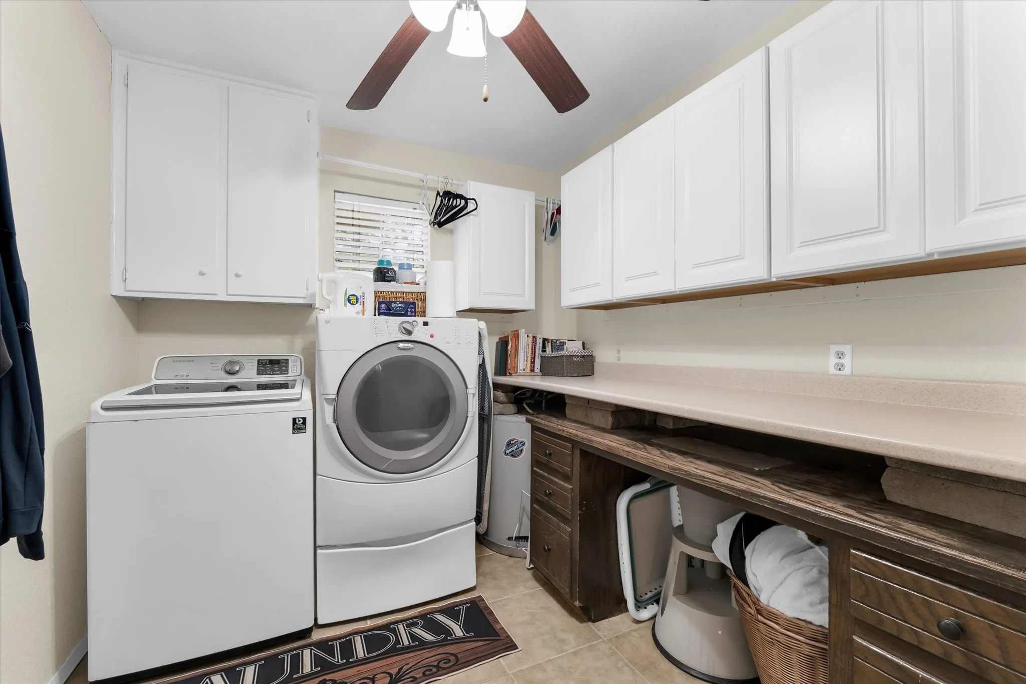 Utility room featuring white cabinetry, a light-toned countertop, and a wood-finish built-in desk