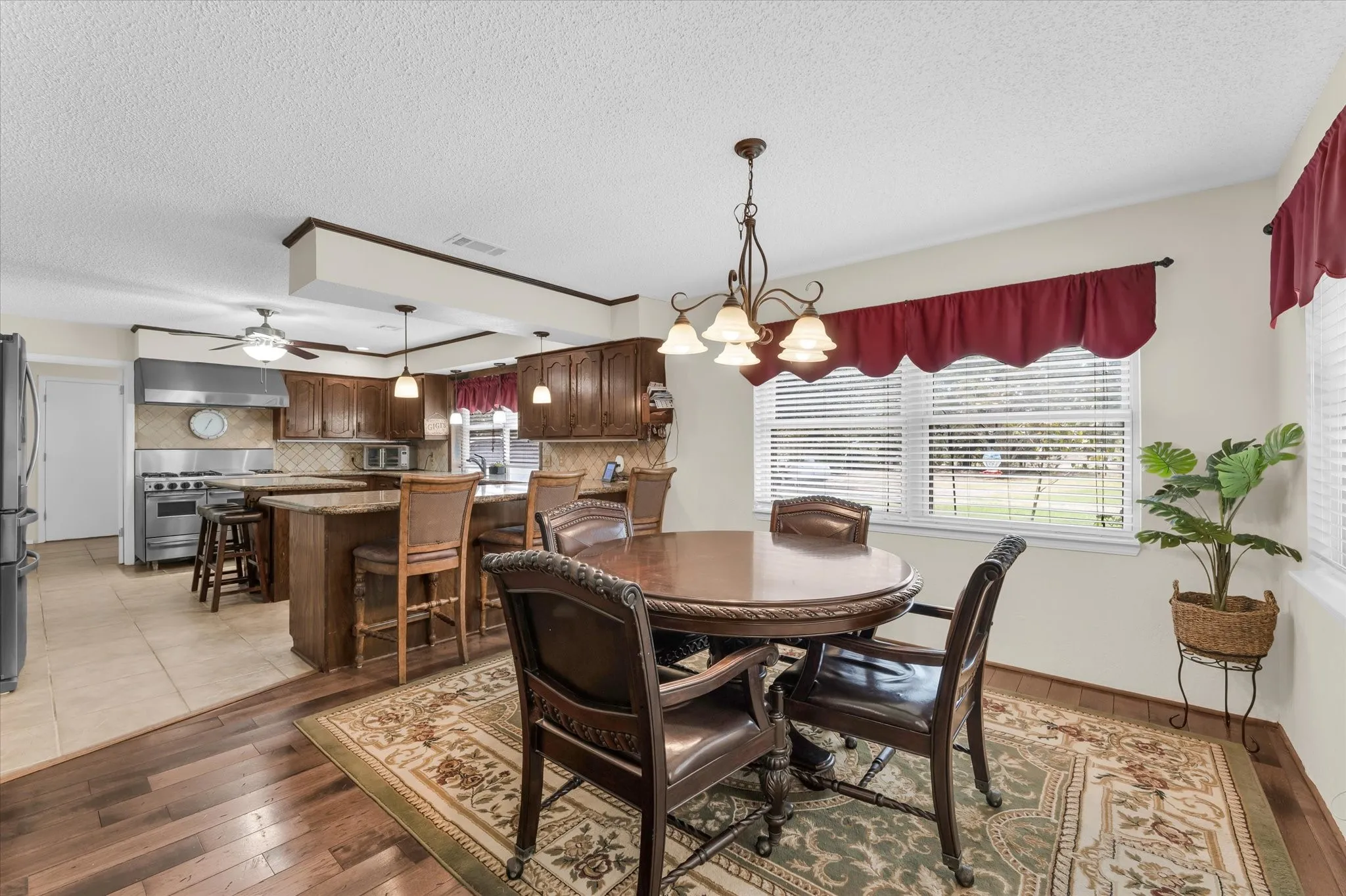 Open concept kitchen and dining space featuring wood-finish flooring, a kitchen island with seating, dark wood cabinetry, and stainless steel appliances