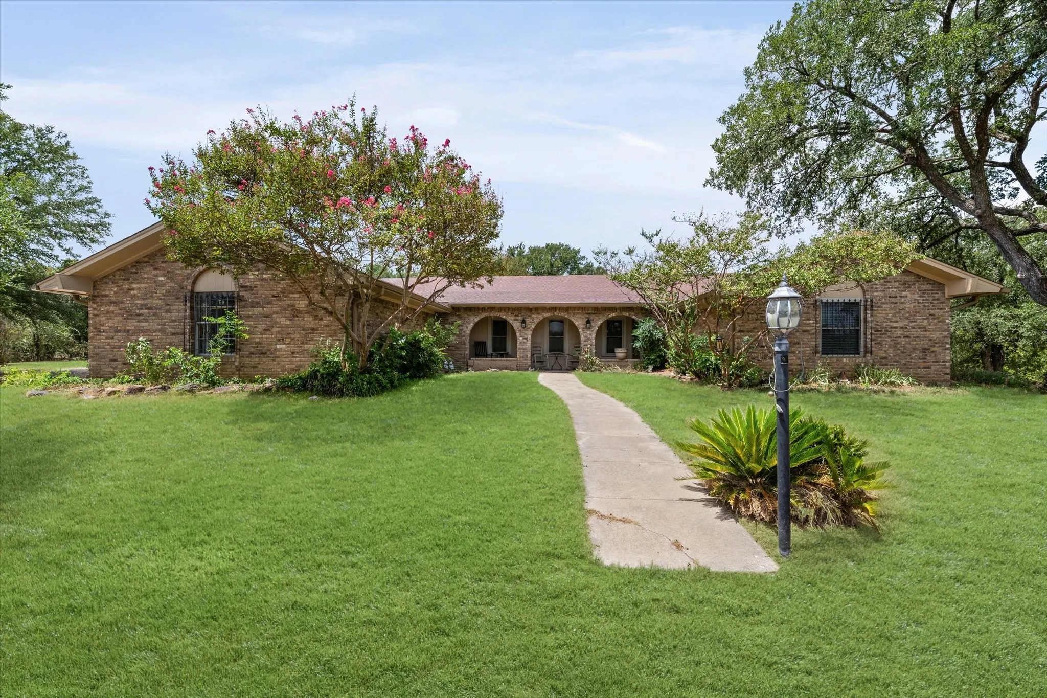Brick exterior residence featuring a curved walkway leading to the entrance