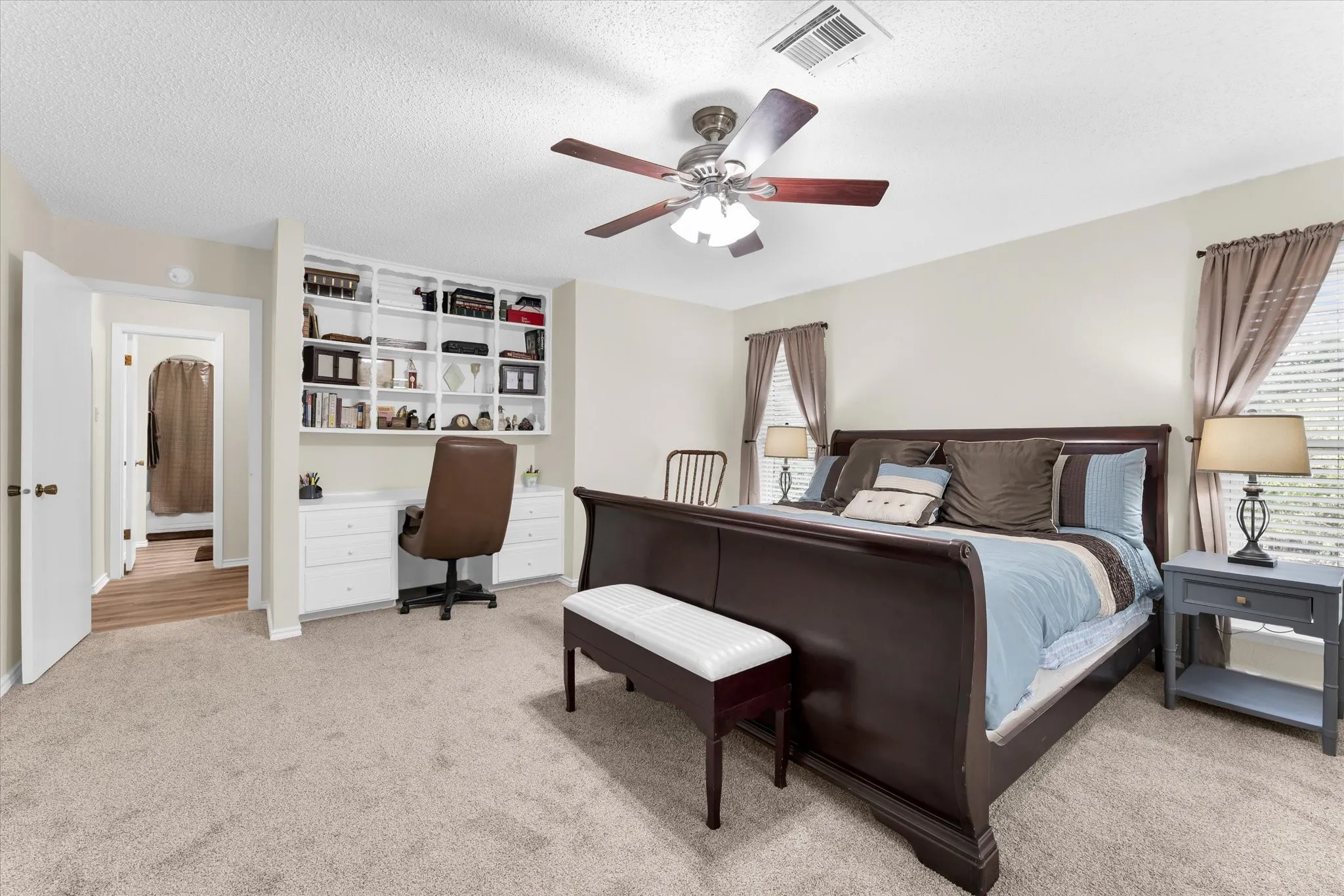 Neutral-toned carpeting in a bedroom featuring a ceiling fan with integrated lighting