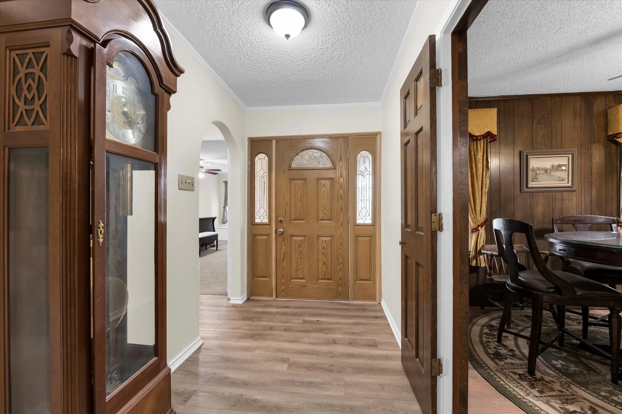 Entryway featuring a wood-finish door with decorative glass sidelights, light wood-finish flooring, and an arched doorway