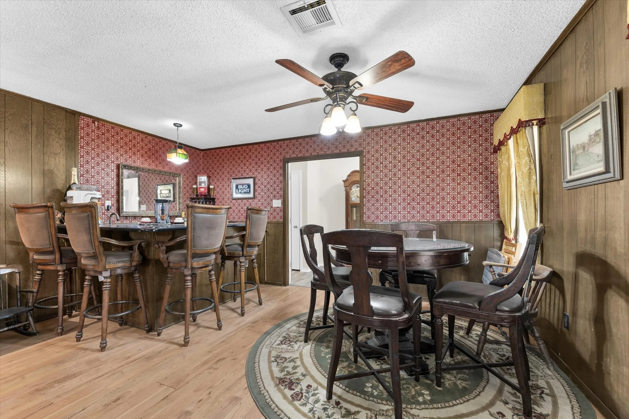 Entertainment space featuring a built-in bar with seating, wood-finish flooring, and a ceiling fan with integrated lighting