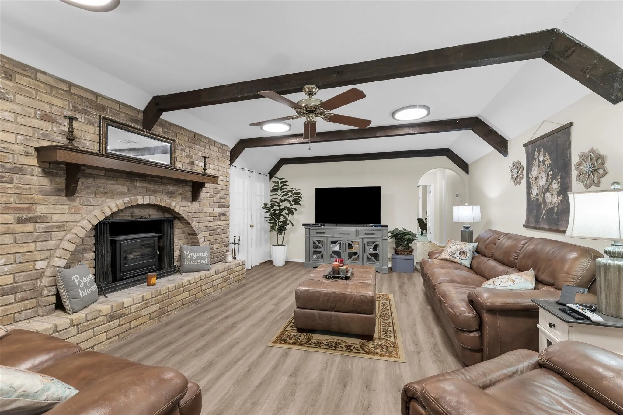 Vaulted ceiling living area featuring wood-finish flooring and exposed ceiling beams