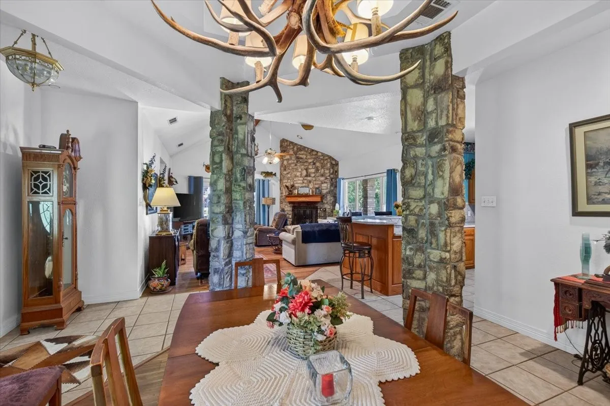 Formal dining area with tile flooring and a vaulted ceiling (Custom antler light is excluded).