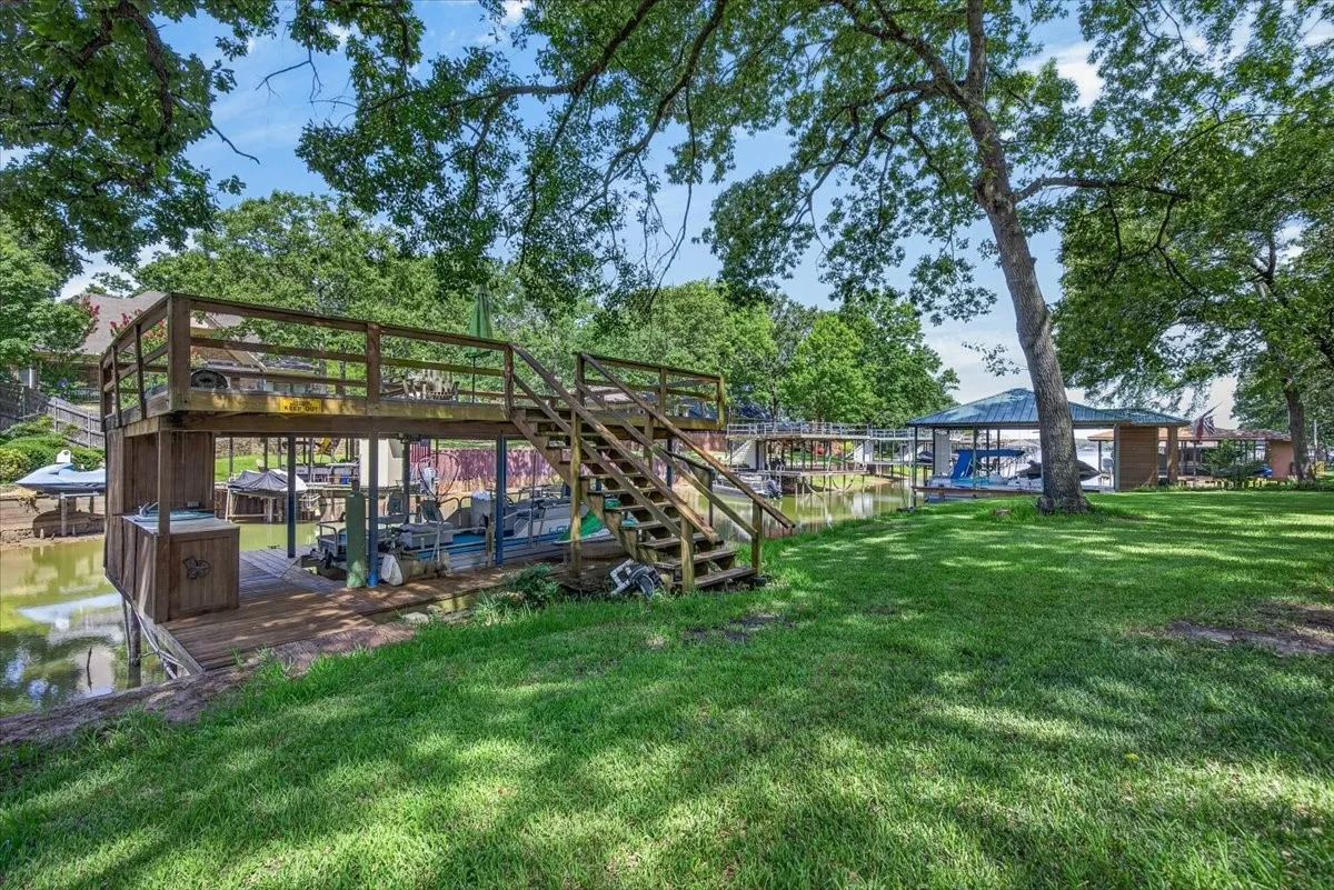 Two-story wooden boat house featuring a covered pontoon boat slip, external staircase, and upper-level deck.  Plenty of fish stories and swimming happens right here.