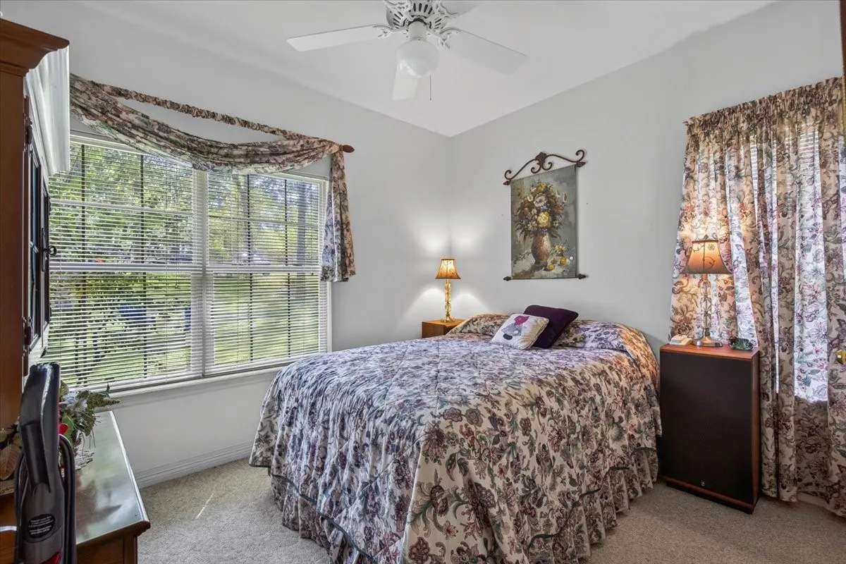 Bedroom with double-hung window with horizontal blinds, providing natural light