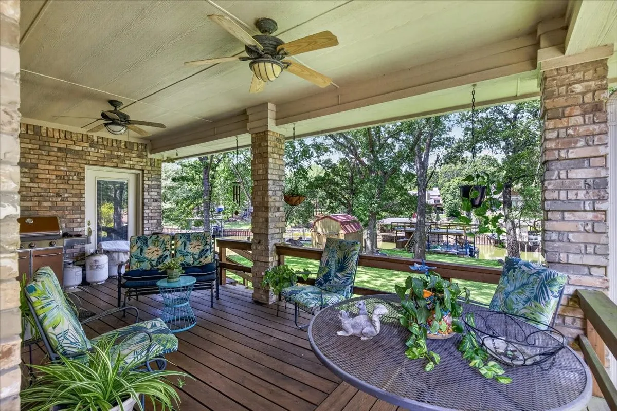 You will not want to leave this spot - Spacious covered patio with wood-finish decking, brick and stone columns, and ceiling fans to enjoy the lakeside views and listen to the wildlife and breeze blowing through the trees.