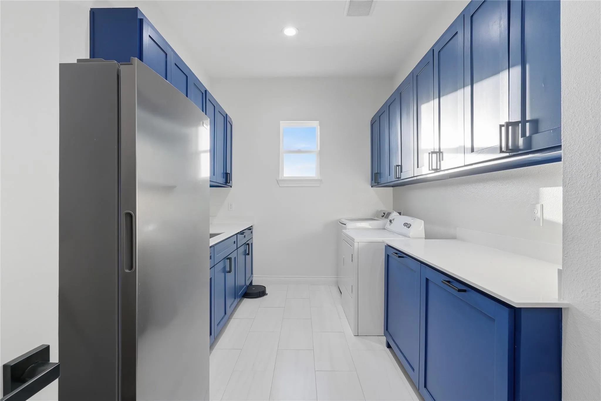 White tile flooring, custom blue cabinetry, and white countertops