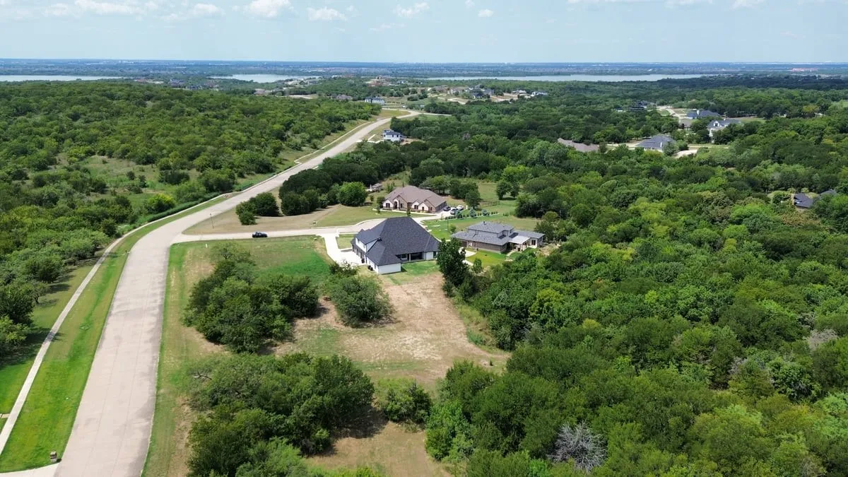 Expansive natural surroundings with a paved roadway and scattered residential structures