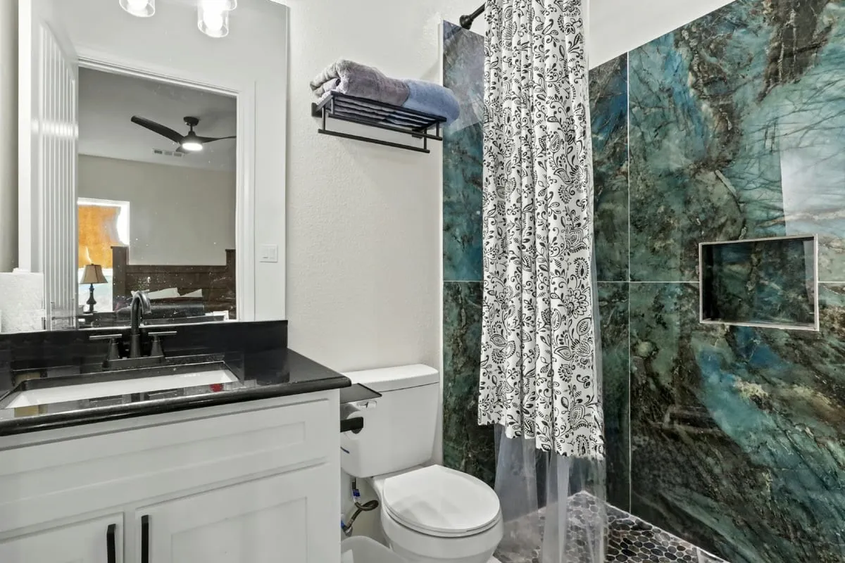 White vanity with black countertop and undermount sink, matte black faucet, and a large wall mirror