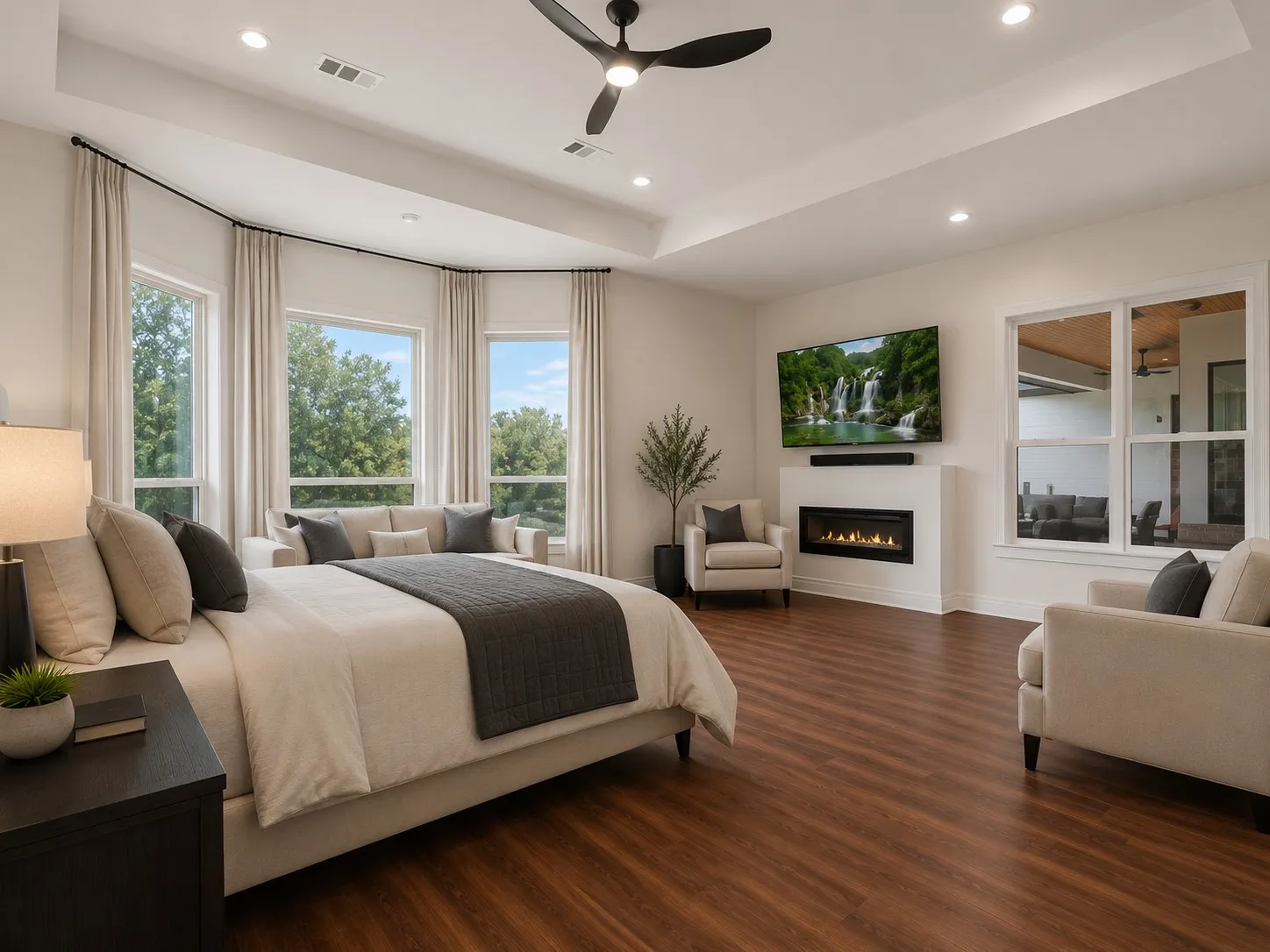 Expansive room featuring wood-finish flooring, a contemporary fireplace, and a tray ceiling with recessed lighting