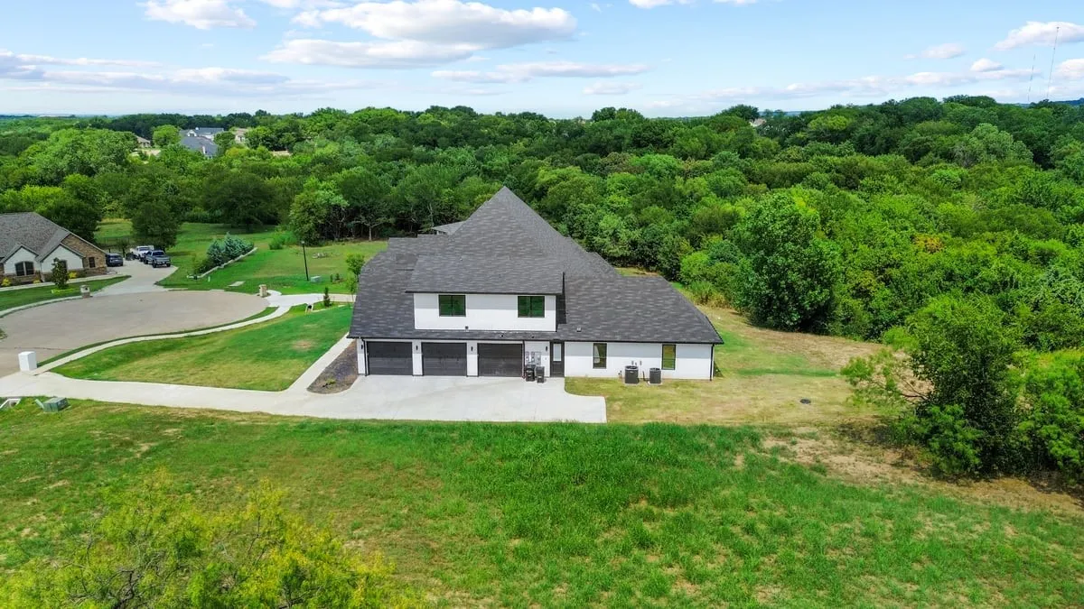 Modern architectural home set on expansive grounds with manicured lawns and mature tree-lined perimeter