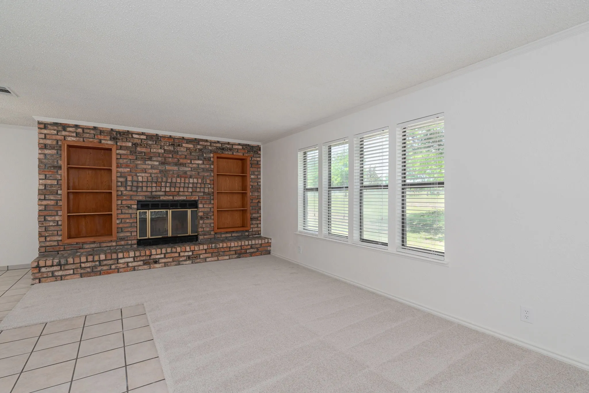 Floor-to-ceiling brick fireplace with built-in shelving creates a warm focal point for family gatherings.