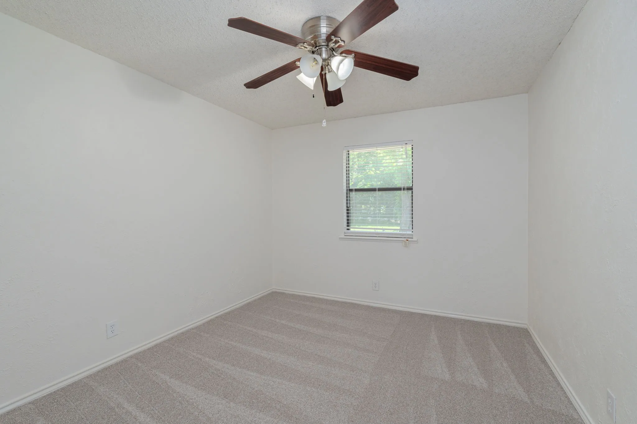 Comfortable secondary bedroom with plush carpet, ceiling fan, and abundant natural light.
